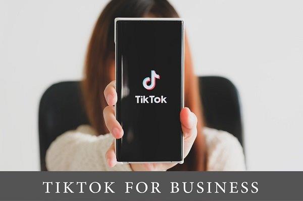 the girl is holding a phone pointed at the screen whose display is the TickTok logo